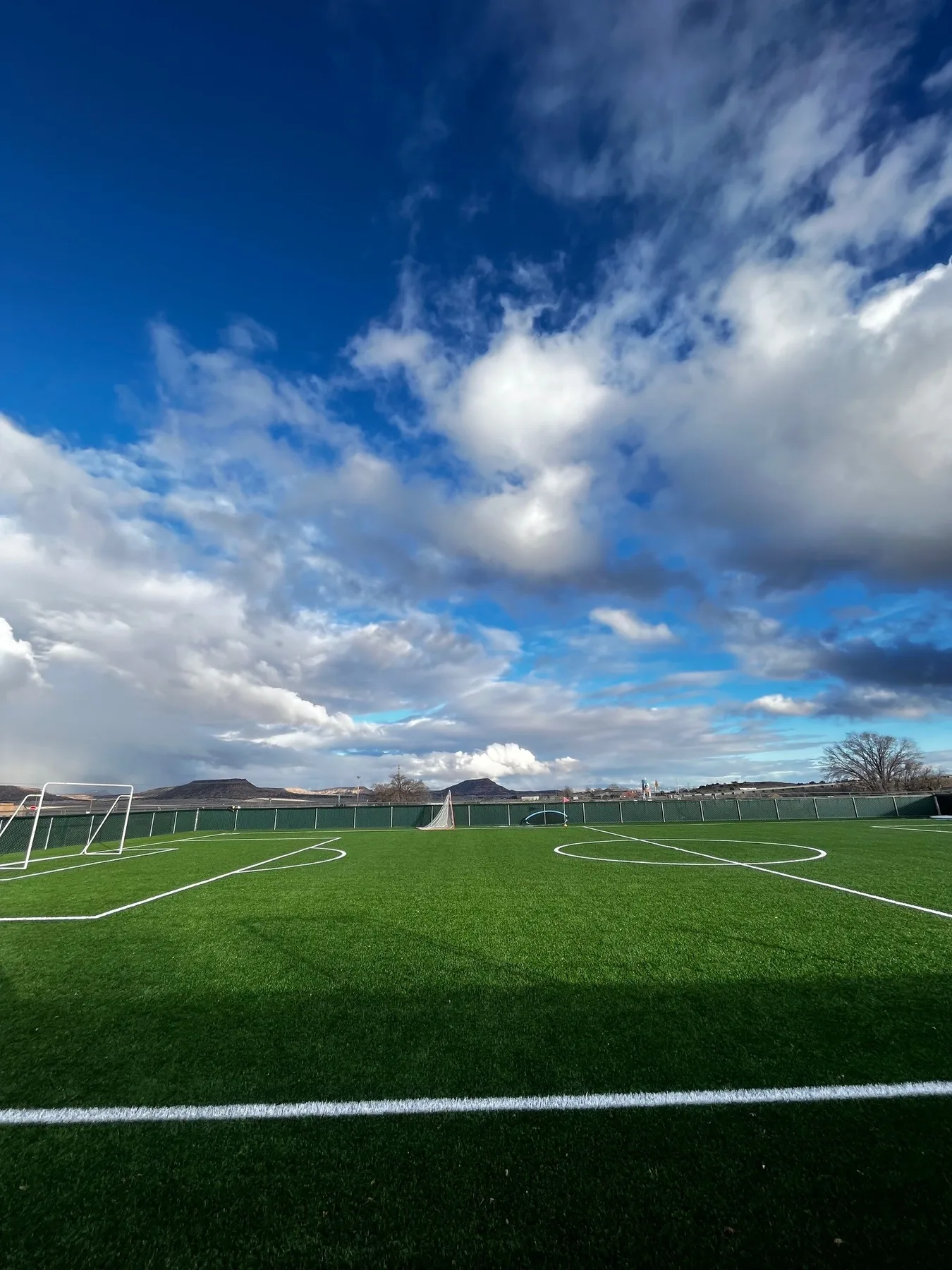 Finished Baca artificial-turf soccer pitch under a big cloudy sky